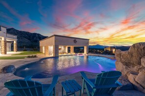 A modern building with a pool, green chairs, and a mountainous backdrop. - Phoenix Mansion w/ Pool & Spa | Mtn & City Views (Laveen)