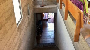 A narrow staircase with a wooden horse sculpture at the top, leading to a room with a bed and colorful pillows.