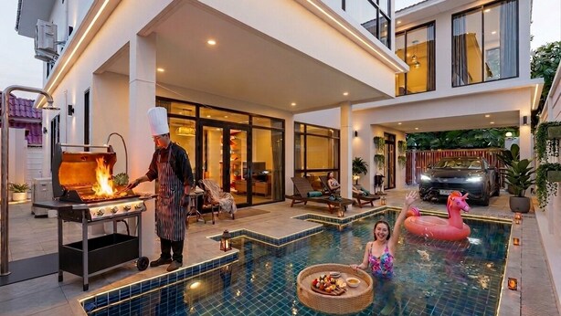 A poolside area with a grill, lounge chairs, and a pool with a flamingo float. - Private pool VIlla in Pattaya central near walking street 7BR luxury pool table (Muang Pattaya)