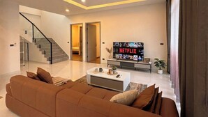 A modern living room with a staircase, a flat-screen TV, and a coffee table. - Private pool VIlla in Pattaya central near walking street 7BR luxury pool table (Muang Pattaya)