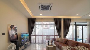 A modern living room with a flat-screen TV, a sofa, a coffee table, and a fan. - Private pool VIlla in Pattaya central near walking street 7BR luxury pool table (Muang Pattaya)