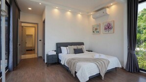 A bedroom with a bed, bedside tables, a window with curtains, and a door leading to another room. - Private pool VIlla in Pattaya central near walking street 7BR luxury pool table (Muang Pattaya)