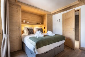 A wooden-paneled bedroom with a bed, pillows, and a green blanket. - Wifi, 100m from resort center, 2nd floor, fitness, swimming pool, sauna, hammam, balcony, tv (Les Gets)
