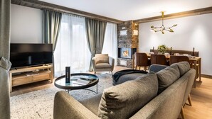 A modern living room with a television, sofa, dining table, and fireplace. - Wifi, 200m from ski slopes, 2nd floor, fitness, swimming pool, sauna, hammam, balcony, tv (Les Gets)