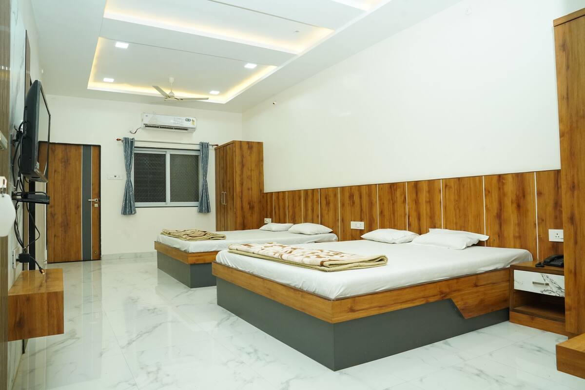 A modern bedroom with a large bed, bedside tables, a wardrobe, and an air conditioning unit.
