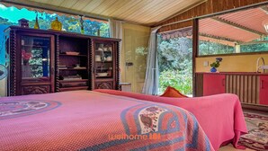 Una camera da letto con un letto grande, un armadietto in legno e vista sul verde.