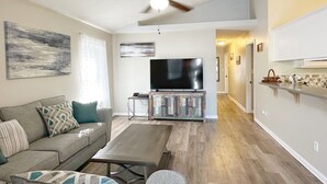Ein Wohnzimmer mit Sofa, Couchtisch, Fernseher und Deckenventilator.