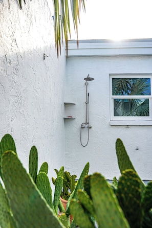 A white exterior wall with a window, a showerhead, and a potted plant. - Cozy Villa Near Clearwater Beach with Patio & Hammock (Clearwater)