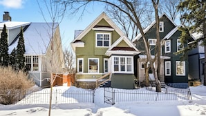 Zona residencial con casas, suelo cubierto de nieve y una cerca de metal.