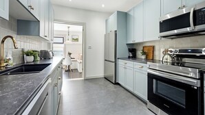 Una cocina moderna con electrodomésticos de acero inoxidable, armarios azul claro y encimera negra.