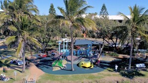 A playground with slides and climbing structures surrounded by palm trees. - Unit 13 Lakeview Park Bargara (Bargara)