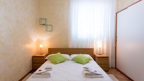 A hotel room with a bed, two bedside tables, a window with curtains, and a wall-mounted light fixture. - Roman Holiday Home Re di Roma (Rome)