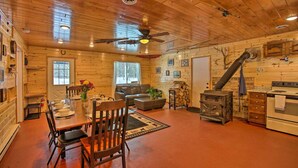 Ein Holzblockhaus-Interieur mit Essbereich, Sofa, Kamin und Küche.