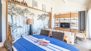 Una moderna camera d'hotel con un letto grande, una TV, un'area pranzo e una parete decorata con opere d'arte.