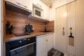 Una cocina compacta con microondas, lavavajillas y encimera de madera.