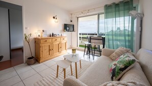 Ein Wohnzimmer mit einer Couch, einem kleinen Tisch, einem Holzschrank und einem Fernseher.