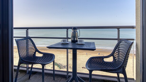 A balcony with a table and two chairs, overlooking a beach. - L'Étoile de Mer - Vue sur la Plage de Bray-Dunes (Bray-Dunes)