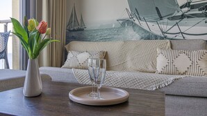 A living room with a sofa, a vase with tulips, and a tray with two glasses. - L'Étoile de Mer - Vue sur la Plage de Bray-Dunes (Bray-Dunes)