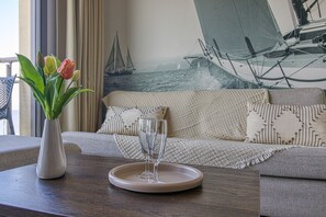 Ett vardagsrum med en soffa, en vas med tulpaner och ett bricka med två glas.