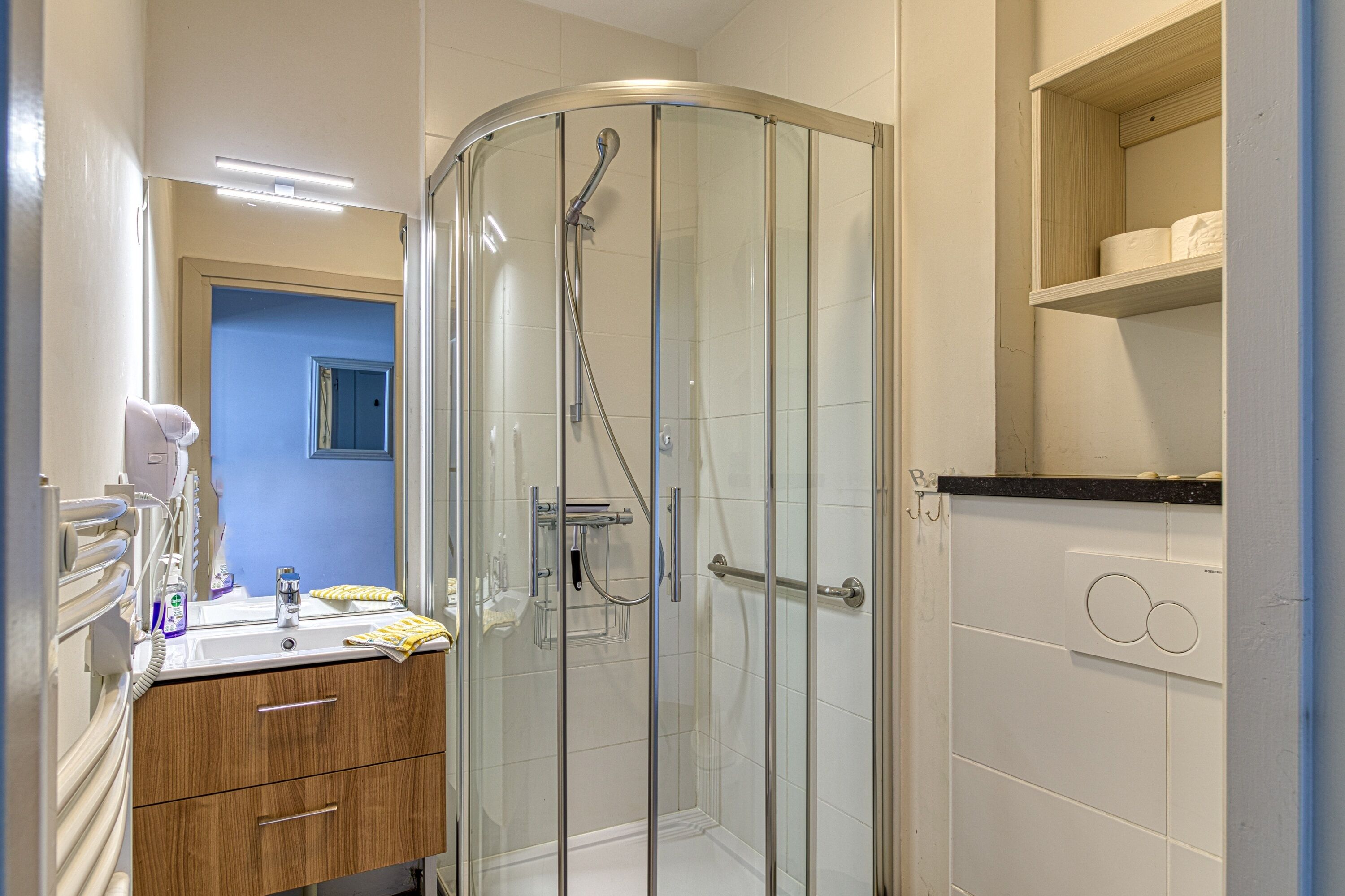 Un baño con cabina de ducha de vidrio, un lavamanos con espejo y un inodoro.