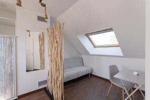 A room with a sloped ceiling, a skylight, a sofa, a chair, and a wooden decorative piece. - Au Clos du Magnolia - Grande maison pour 10 (Pléneuf-Val-André)