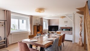 Uma sala de jantar com uma mesa posta para quatro pessoas, uma televisão e uma lareira.