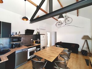 Una cocina moderna con zona de comedor, vigas de madera y una bicicleta decorativa.