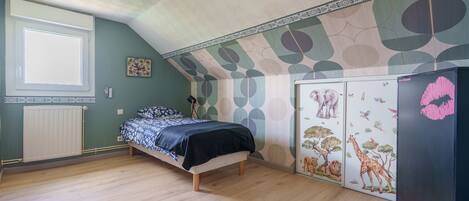 Un dormitorio con cama, radiador, armario y una pared con diseño de hojas.