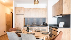 Ett modernt kök med träskåp, ett matbord med plats för sex personer och en inbyggd ugn.