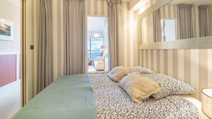 Ein Hotelzimmer mit Bett, Vorhängen, einem Spiegel und Blick ins Freie.