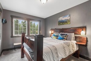 A bedroom with a wooden bed, two windows, a nightstand, and a wall-mounted lamp. - 2 Bedroom Cabin with Fireplace (West Glacier)