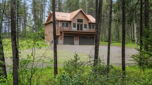 A two-story log cabin with a metal roof, two garage doors, and a front porch. - 2 Bedroom Cabin with Fireplace (West Glacier)
