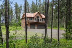 A two-story log cabin with a metal roof, two garage doors, and a front porch. - 2 Bedroom Cabin with Fireplace (West Glacier)