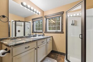 A bathroom with a vanity, a mirror, a shower, and a window. - 2 Bedroom Cabin with Fireplace (West Glacier)