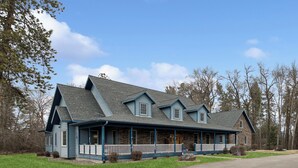 Une maison à deux étages avec une façade en pierre, un porche à l’avant et une allée.