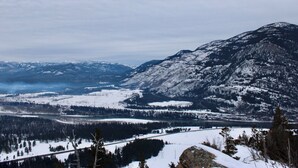 Un paysage montagneux aux sommets enneigés et une vallée abritant un lac.