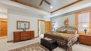 Une chambre à coucher comprenant un lit, une commode, un miroir et un ventilateur de plafond.
