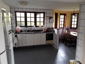 Eine Küche mit weißen Schränken, einer Spüle und einem Essbereich mit Holztischen und einer Tischplatte.