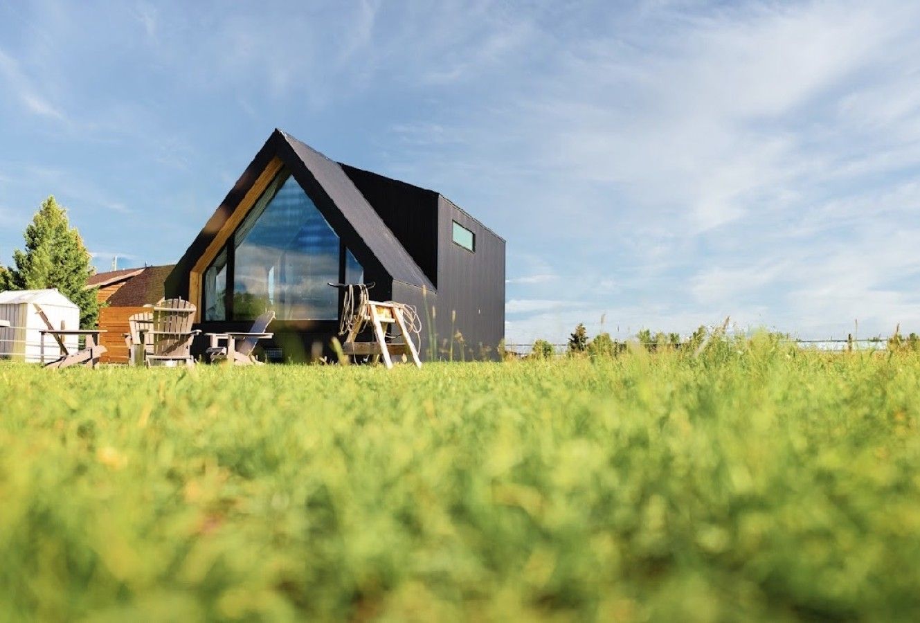 A modern house with a large glass window, a wooden deck, and a clear sky.