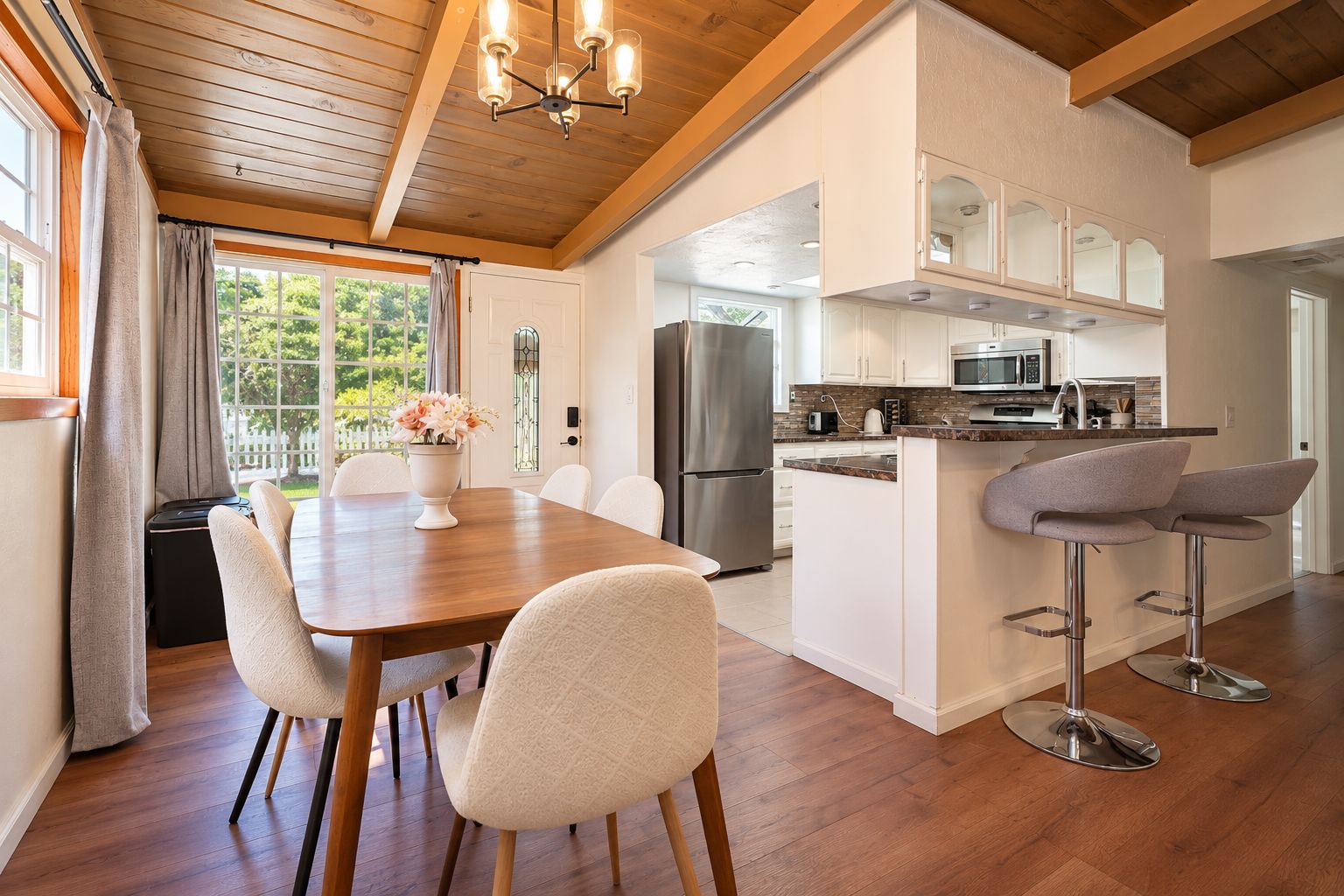 A modern kitchen with a central island, stainless steel appliances, and a dining area with a wooden table and chairs.