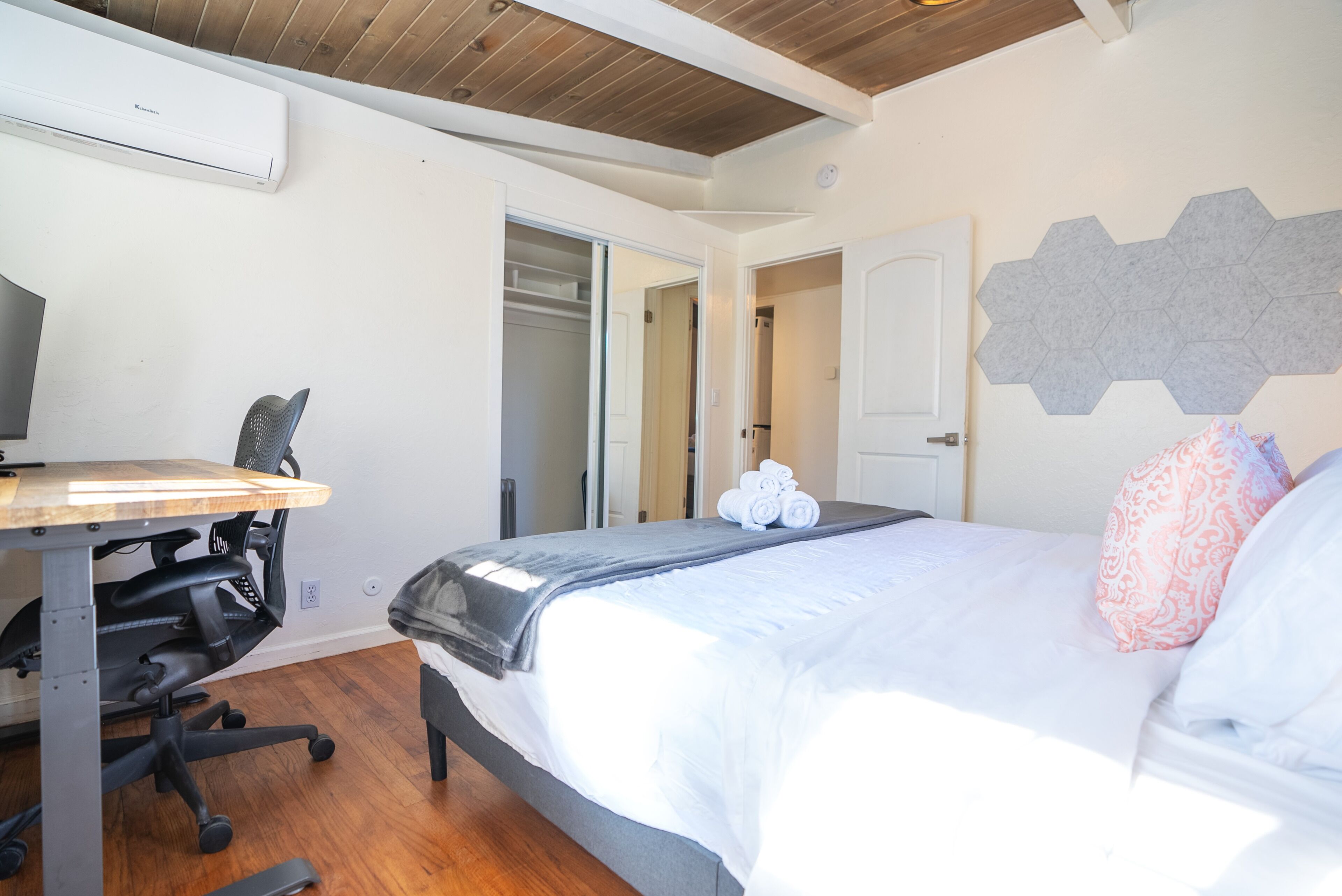 Un dormitorio con cama, escritorio, silla y armario.