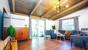 A spacious living area with wooden flooring, a sofa set, a coffee table, and a TV. - Central 3BR 2BA Near Santana Row & Valley Fair (San Jose)
