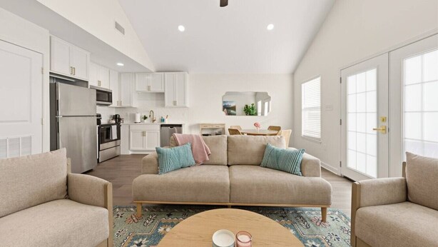 A spacious living room with a beige sofa, a coffee table, and a ceiling fan.