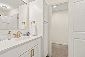 A modern bathroom with a white vanity, gold fixtures, and a large mirror. - Royal Inn-KING-Lux Amenities-Fast WiFi-Balcony (Lafayette)