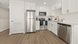 Una cucina moderna con mobili bianchi, elettrodomestici in acciaio inossidabile e pavimento in legno.