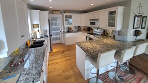 A kitchen with white cabinets, granite countertops, a built-in oven, and a microwave.