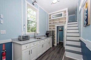 A kitchen with white cabinets, a toaster, a sink, and a window. - Harbor Blue (Anderson)