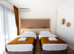 Een hotelkamer met twee bedden, een hoofdeinde, een nachtkastje, een lamp en een spiegel.