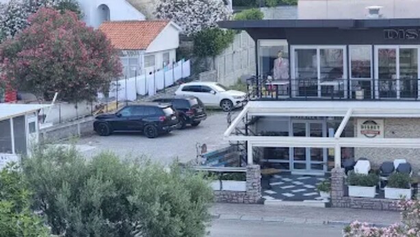 Un bâtiment doté d’un espace extérieur abrité avec des sièges, d’un parking et d’un petit jardin.
