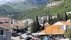 Un quartier résidentiel avec des immeubles, des voitures garées et un paysage montagneux en arrière-plan.